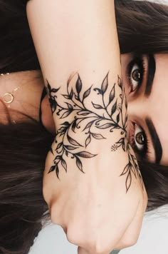 a woman's hand with a tattoo on her left wrist and the other arm behind her head