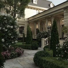 a house with many trees and bushes around it's front yard, as well as a clock on the building