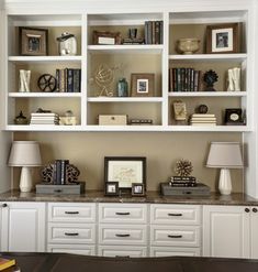 a living room filled with lots of white furniture and bookshelves on top of each other