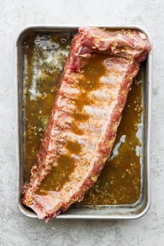 an uncooked piece of meat sitting on top of a pan filled with sauce