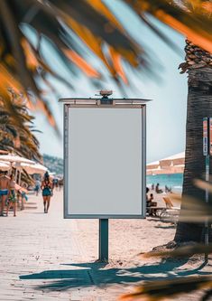 an empty sign stands on the sidewalk next to palm trees and people walking in the background