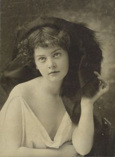 an old black and white photo of a woman with a cat on her shoulder,