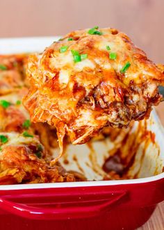 a spoonful of lasagna casserole being lifted from a red dish