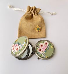 two compact mirrors and a drawstring bag on a white surface