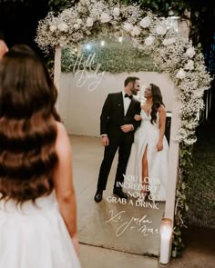 a bride and groom standing in front of a photo frame with the words, you look incredible now grab a drink