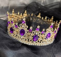 a purple and gold crown sitting on top of a black cloth