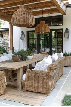 an outdoor dining area with wicker furniture and hanging lights over the table, surrounded by potted plants