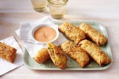 some food is sitting on a plate and next to a cup of dipping sauces