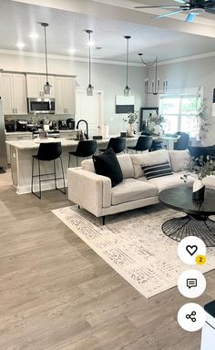 a living room filled with furniture next to a kitchen and dining room table on top of a hard wood floor