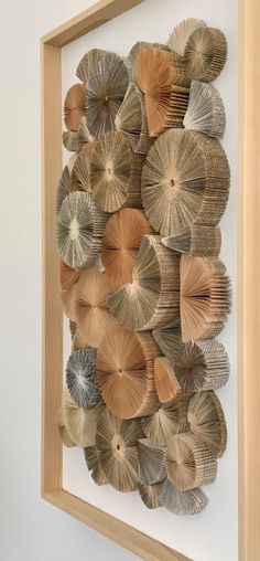 an art piece made out of folded paper and wood sticks is hanging on the wall