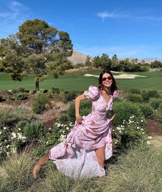 a woman in a pink dress is posing for the camera