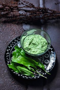 a plate with some greens on it and a small bowl full of green stuff in the middle