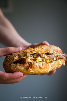 two hands holding a sandwich with meat and cheese