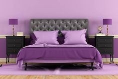 a bed with purple sheets and pillows in a room