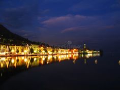 the city is lit up at night with lights reflecting on the water and buildings in the background