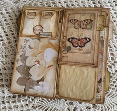 an open book with butterflies on it sitting on top of a doily covered table