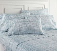 a close up of a bed with blue sheets and pillowcases on top of it