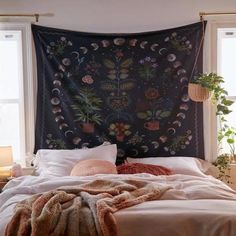 a bed in a bedroom with a tapestry hanging over it's headboard and pillows