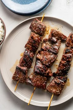 several skewers of meat on a plate with rice