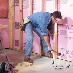 a man in blue shirt working on wall with tools and pink walls under construction area