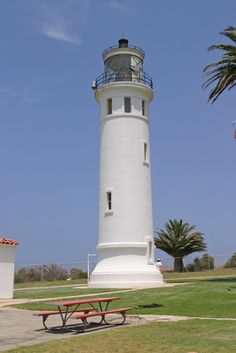 a white lighthouse with a red bench in front of it