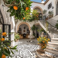 an orange tree is in the middle of a courtyard with stairs and potted plants