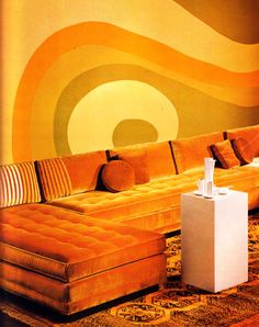 an orange couch and ottoman in front of a large wall mural with circles on it