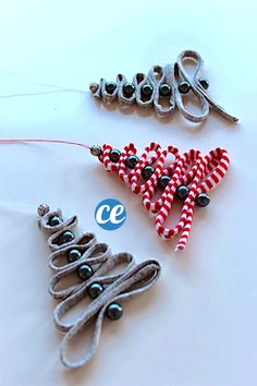 two christmas tree ornaments made out of fabric and beads on a white table with string