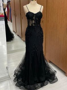 Full of allure and grace, this prom dress captivates with its exquisite detailing and flawless design. The gown features a bodice rich in floral appliques that trail down a figure-hugging silhouette, culminating in a flared tulle skirt that floats with every step. Its transparent midsection adds a touch of intrigue, balanced by the classic elegance of the black fabric. With a blend of traditional beauty and contemporary chic, this dress is an embodiment of the poise and mystery fitting for a night of celebration and sophistication. Black Prom Dress With Butterflies, Black Prom Dresses With Corset, Vintage Corset Prom Dress, Laced Black Prom Dress, Black A Line Prom Dress, Black Prom Dress With Corset, Black Prom Dress Elegant, Masquerade Dress Ideas Prom, Black Corset Dress Prom