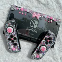 two nintendo wii game controllers with pink and blue crystals on them sitting next to each other