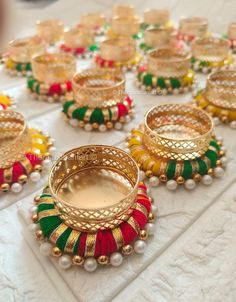 many different colored bracelets and rings on a white table with other jewelry items in the background