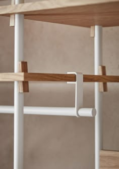 a white shelf with two wooden shelves on top of it and some metal bars attached to the wall