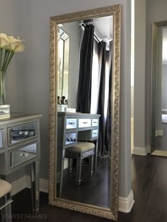 a large mirror sitting on top of a wooden floor next to a desk and chair