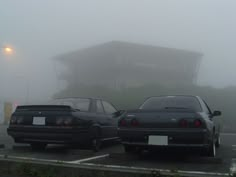 two cars parked in a parking lot on a foggy day