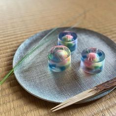 three small candles are on a plate with chopsticks