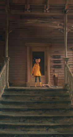 a teddy bear standing on the steps of a house with a yellow coat over it's head