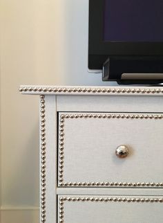 a white dresser with beaded drawers and a flat screen tv