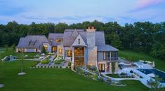 an aerial view of a large home in the middle of a lush green field at dusk