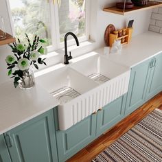 a white kitchen sink sitting under a window next to a vase with flowers in it