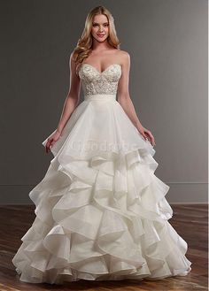 a woman in a white wedding dress standing on a wooden floor with her hands on her hips