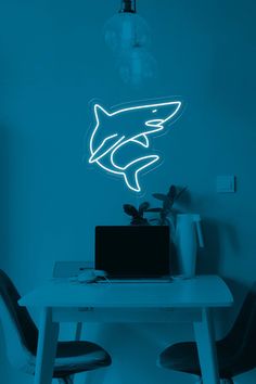 a laptop computer sitting on top of a table under a neon shark wall decal