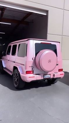 a pink mercedes g - class is parked in front of a garage with its door open