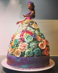 a woman in a dress made out of flowers on top of a cake