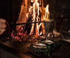 a fire burning in a fireplace with flames coming out of it and some food on the table