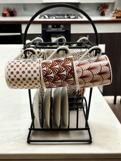 a rack with cups and saucers on top of a kitchen counter next to an oven