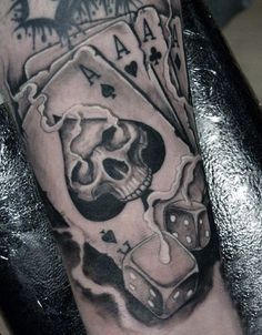 a man's arm with a skull and playing cards tattoo on it