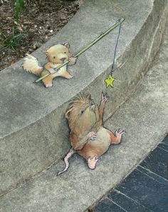 a drawing of two small animals on the side of a concrete wall, one holding a string