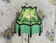 a green lamp sitting on top of a table next to a wallpapered wall