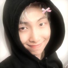 a young man wearing a black hoodie with a pink bow on it's head