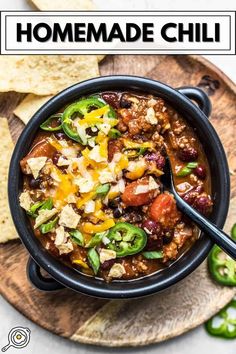 a bowl filled with chili, cheese and tortilla chips on top of a wooden plate